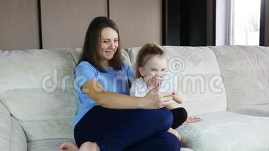 <strong>一家人的</strong>妈妈和小女儿在沙发上用智能手机玩得开心